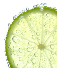 Photo of Fresh lime slice in sparkling water on white background, closeup