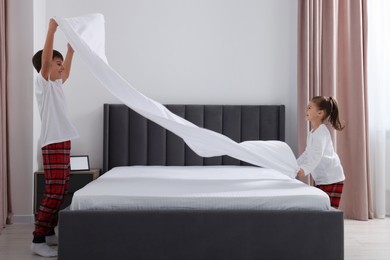 Photo of Brother and sister changing bed linens together in bedroom