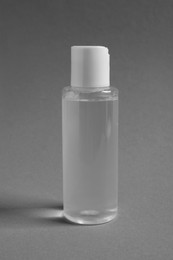 Photo of Transparent bottle with cosmetic product on grey background