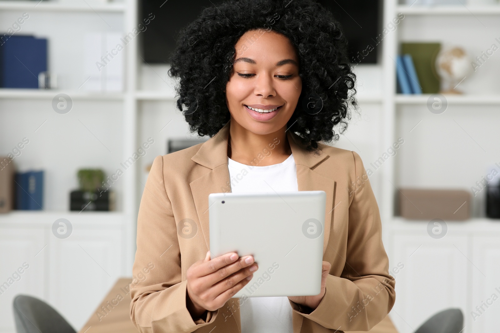 Photo of Smiling young businesswoman using tablet in modern office