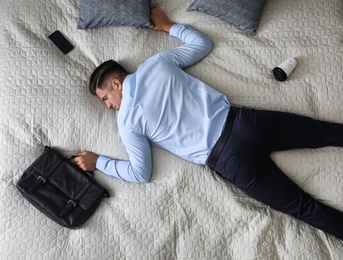 Photo of Exhausted businessman in office wear sleeping on bed at home after work, above view