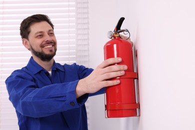 Man checking fire extinguisher indoors, selective focus
