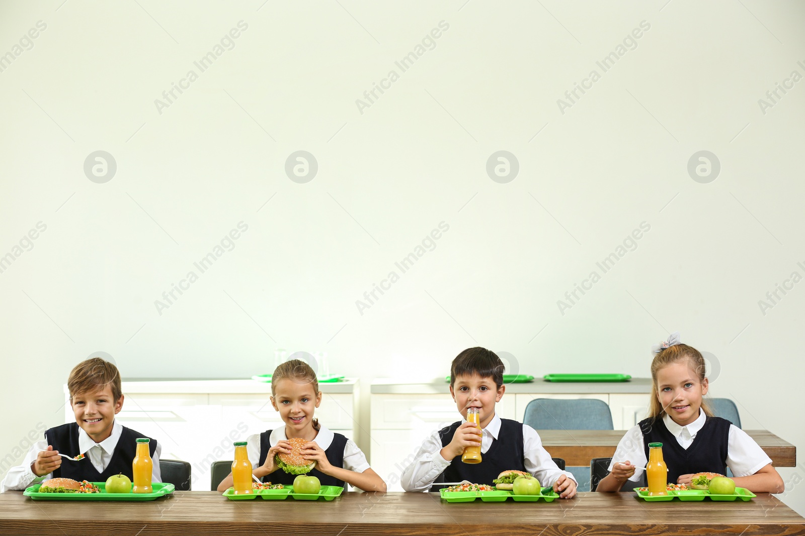 Photo of Happy children eating healthy food for lunch in school canteen