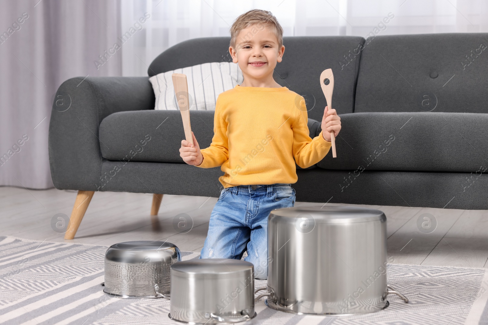 Photo of Little boy pretending to play drums on pots at home