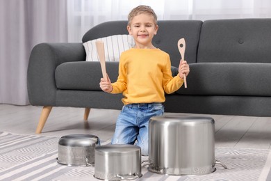 Little boy pretending to play drums on pots at home