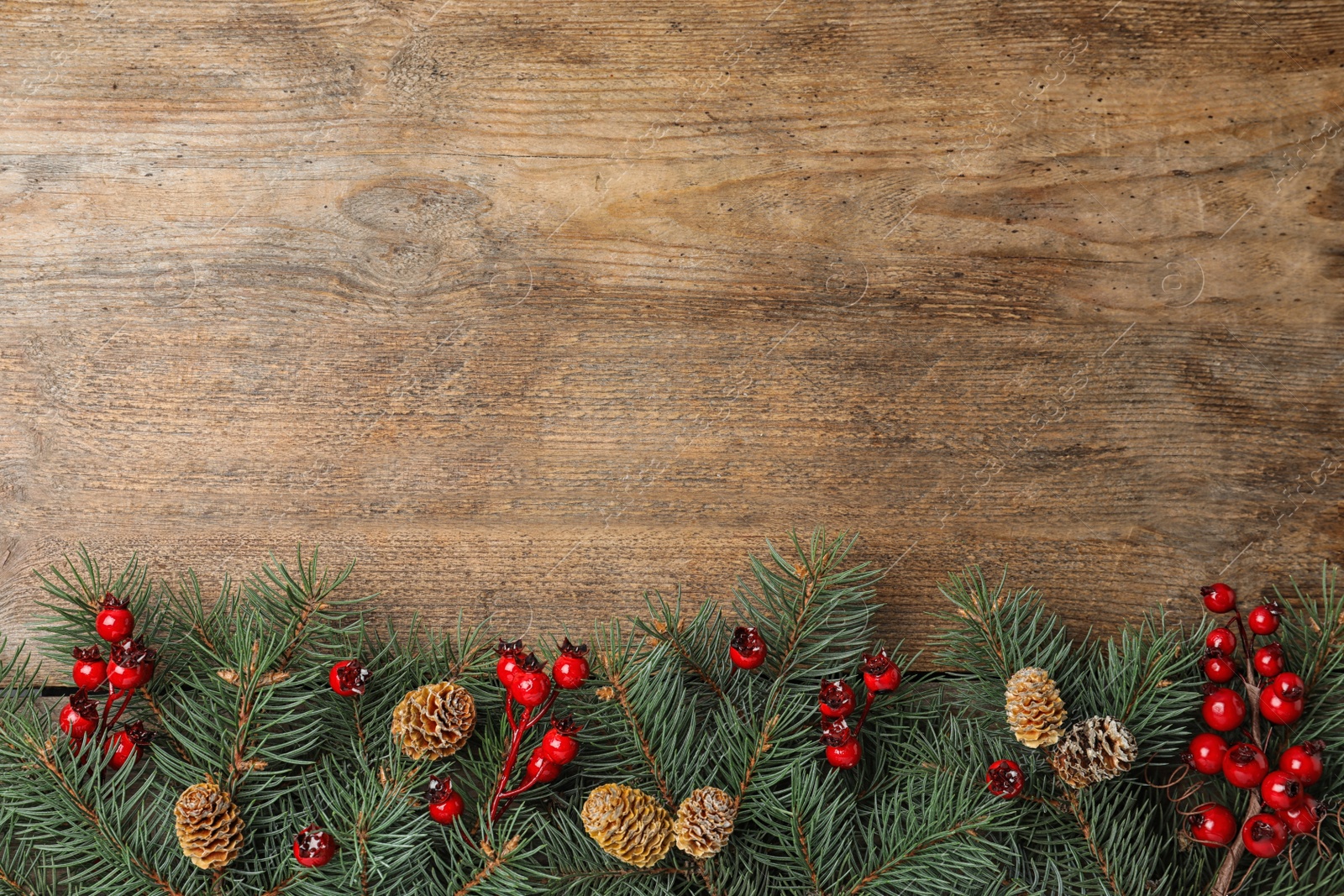 Photo of Flat lay composition with fir branches and berries on wooden background, space for text. Winter holidays