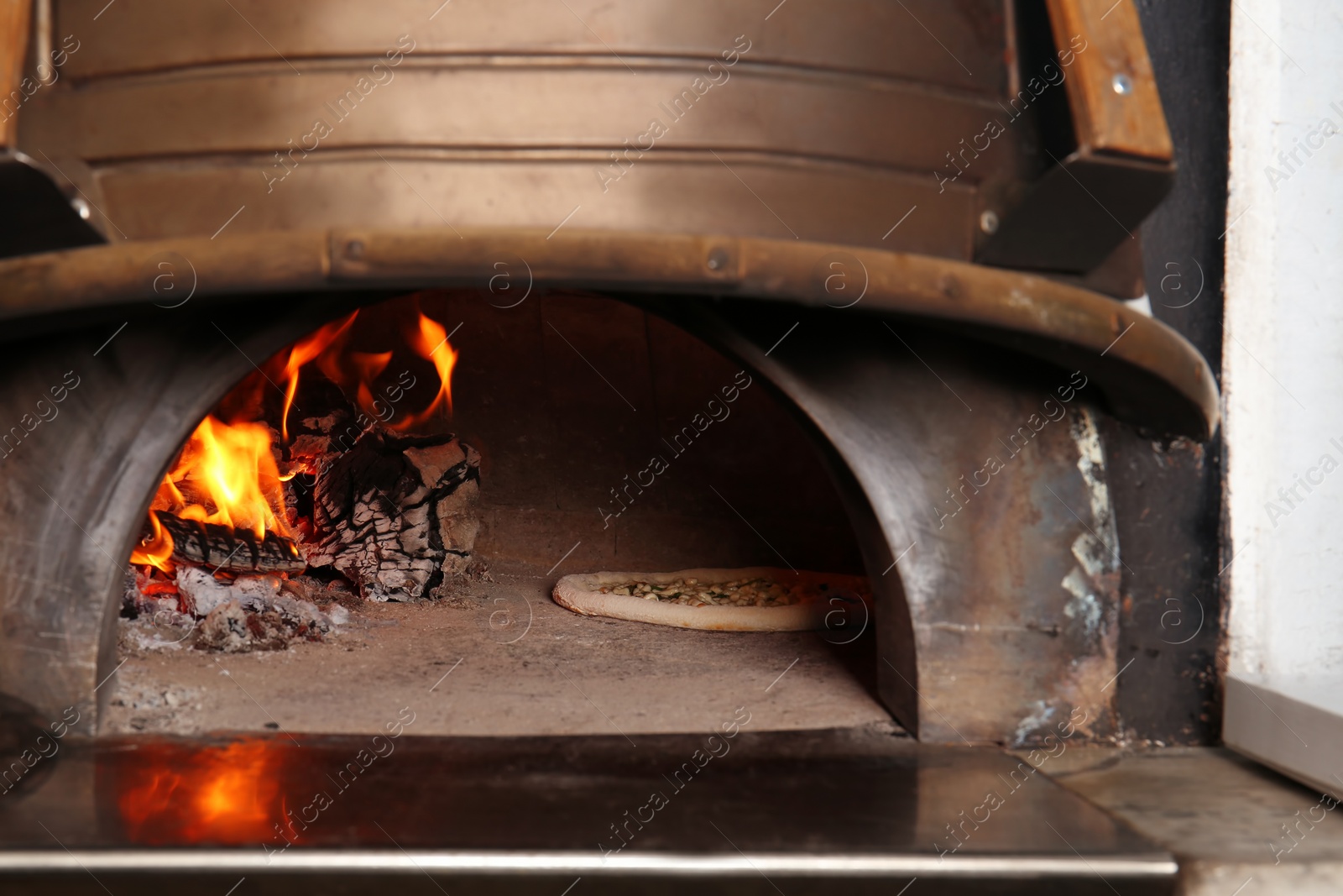 Photo of Oven with burning firewood and tasty pizza in restaurant kitchen