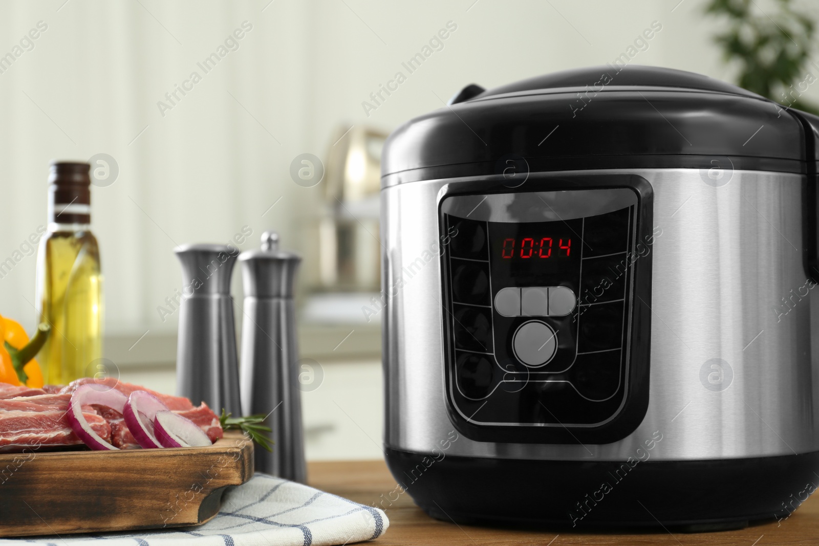 Photo of Modern multi cooker and products on wooden table in kitchen