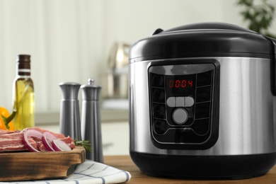 Photo of Modern multi cooker and products on wooden table in kitchen