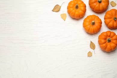 Fresh ripe pumpkins and autumn leaves on white wooden table, flat lay. Space for text