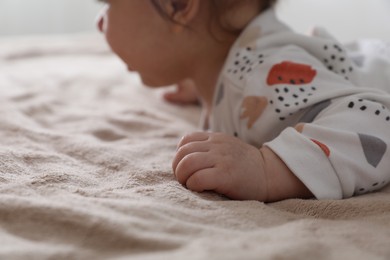 Little baby lying on brown blanket indoors, closeup. Space for text