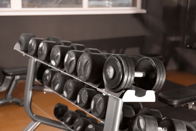 Photo of Dumbbells on rack in gym. Modern sport equipment