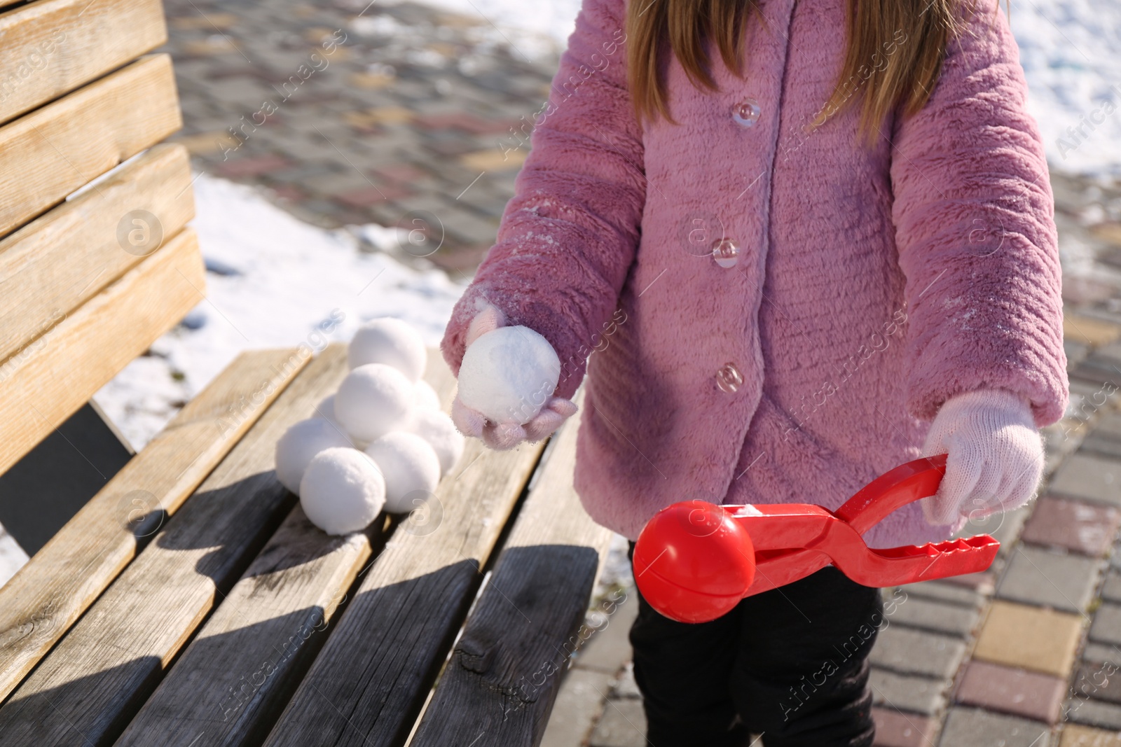 Photo of Little girl playing with snowball maker outdoors, closeup