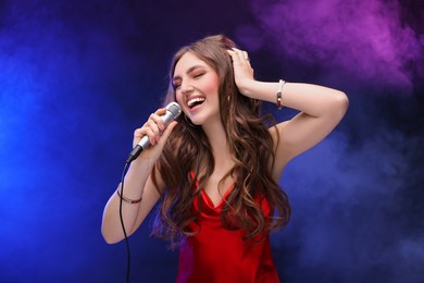 Beautiful woman with microphone singing in color lights