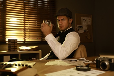 Photo of Old fashioned detective with drink at table in office