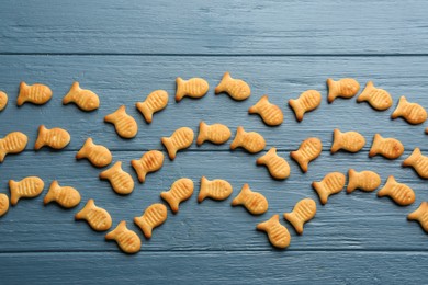 Photo of Delicious goldfish crackers on blue wooden table, flat lay