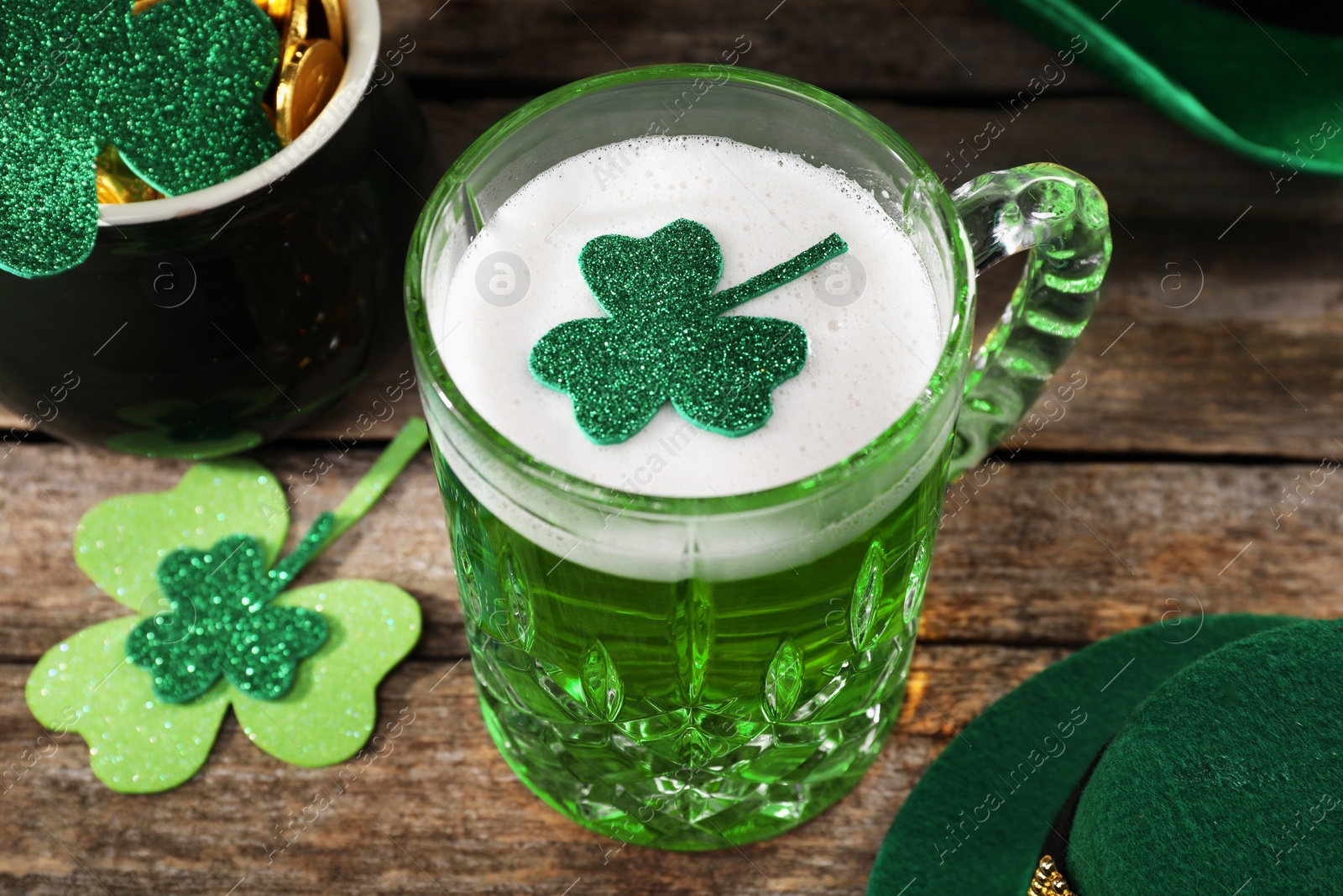 Photo of St. Patrick's day party. Green beer, leprechaun hat, pot of gold and decorative clover leaves on wooden table