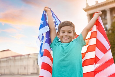 Photo of Cute little boy with American flag on city street