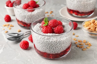 Photo of Delicious chia pudding with raspberries and mint on light marble table