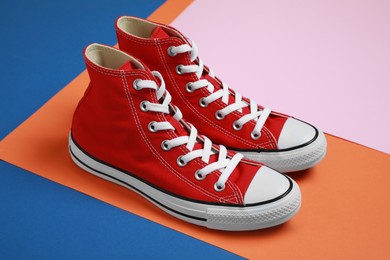 Photo of Pair of new stylish red sneakers on colorful background