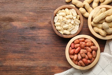 Photo of Fresh peanuts in bowls on wooden table, top view. Space for text