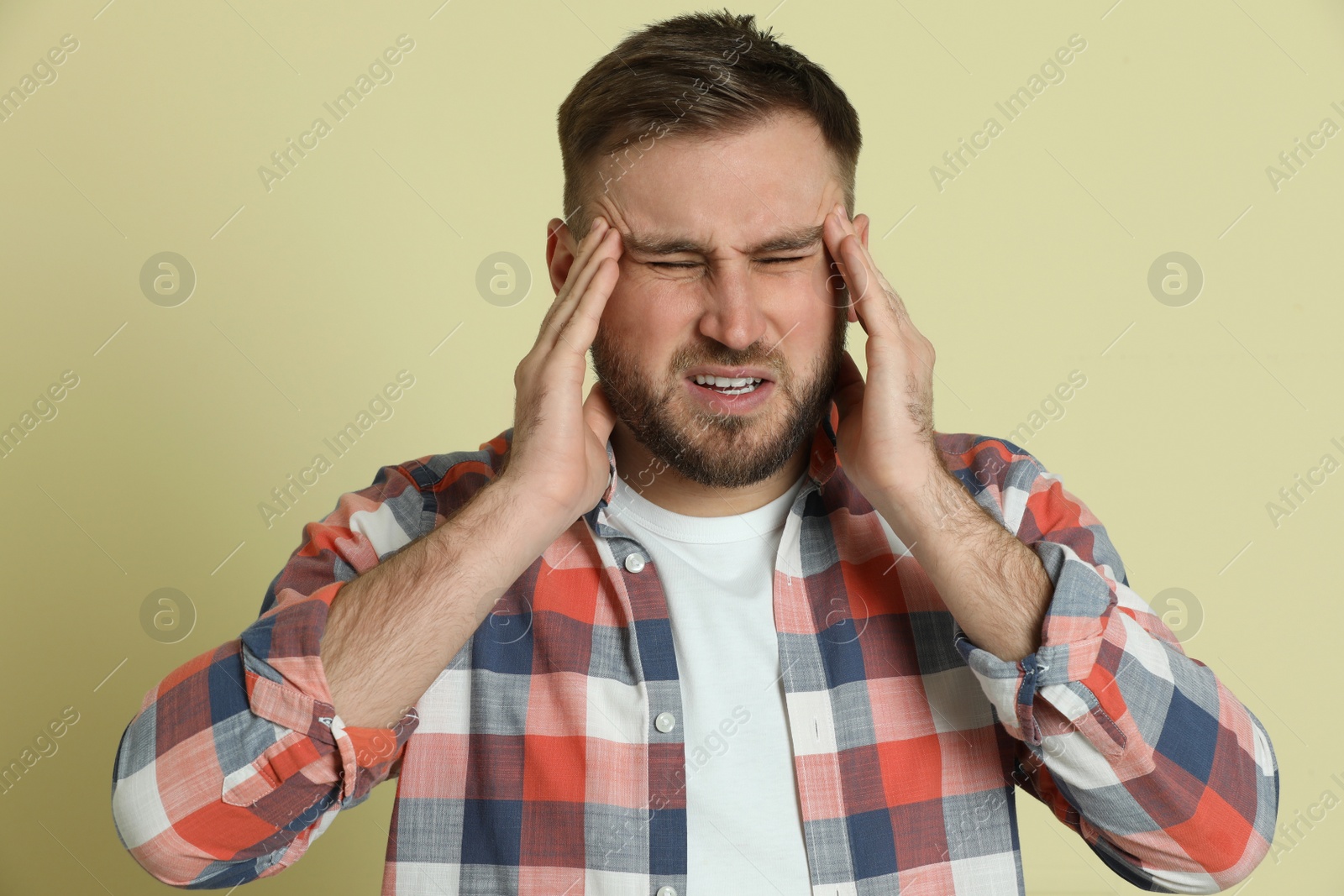 Photo of Man suffering from migraine on light green background