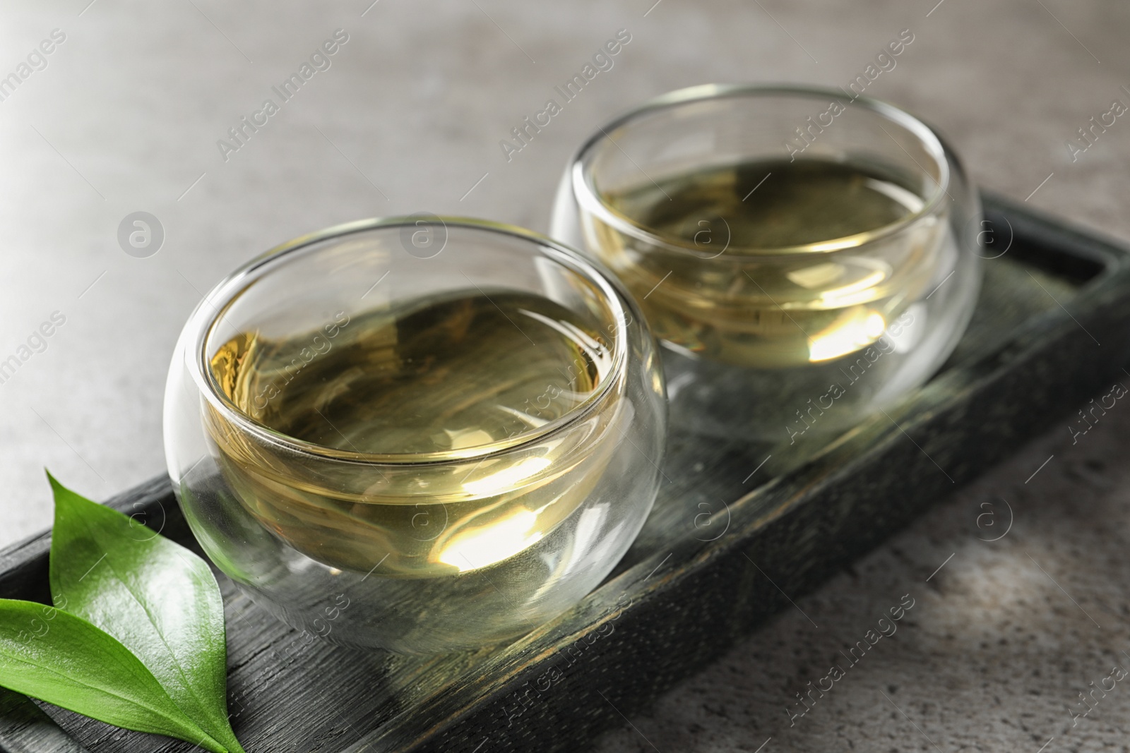 Photo of Glass cups of freshly brewed oolong tea on table, closeup