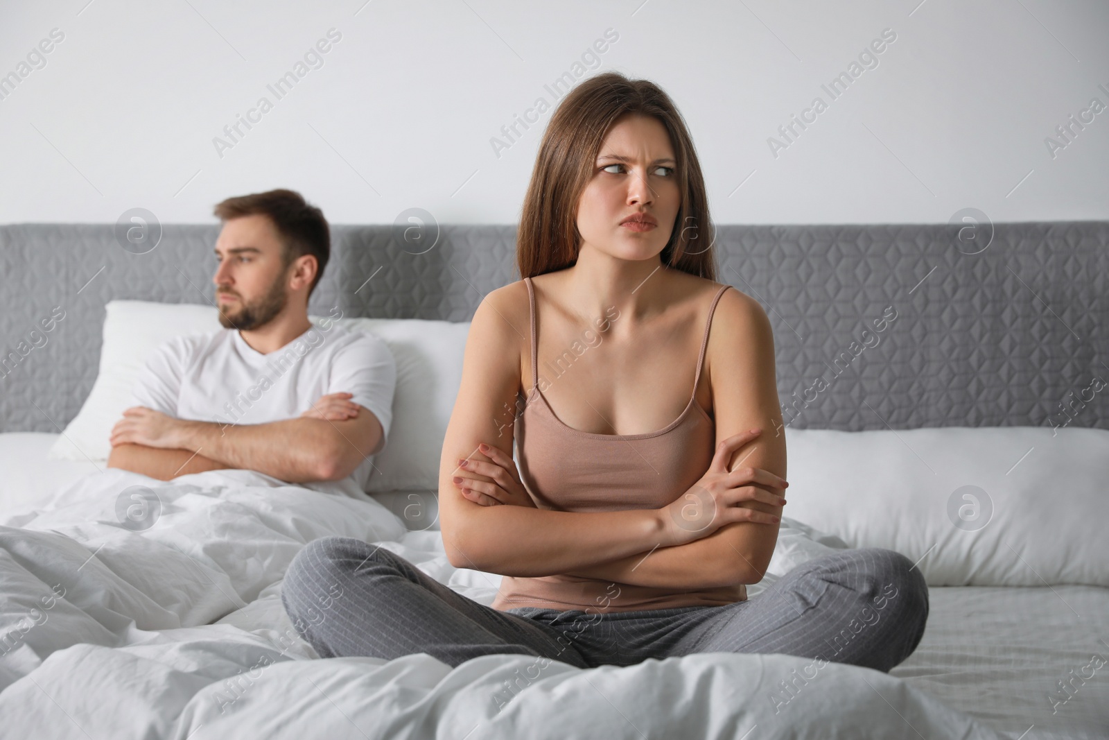 Photo of Unhappy young couple with relationship problems after quarrel in bedroom