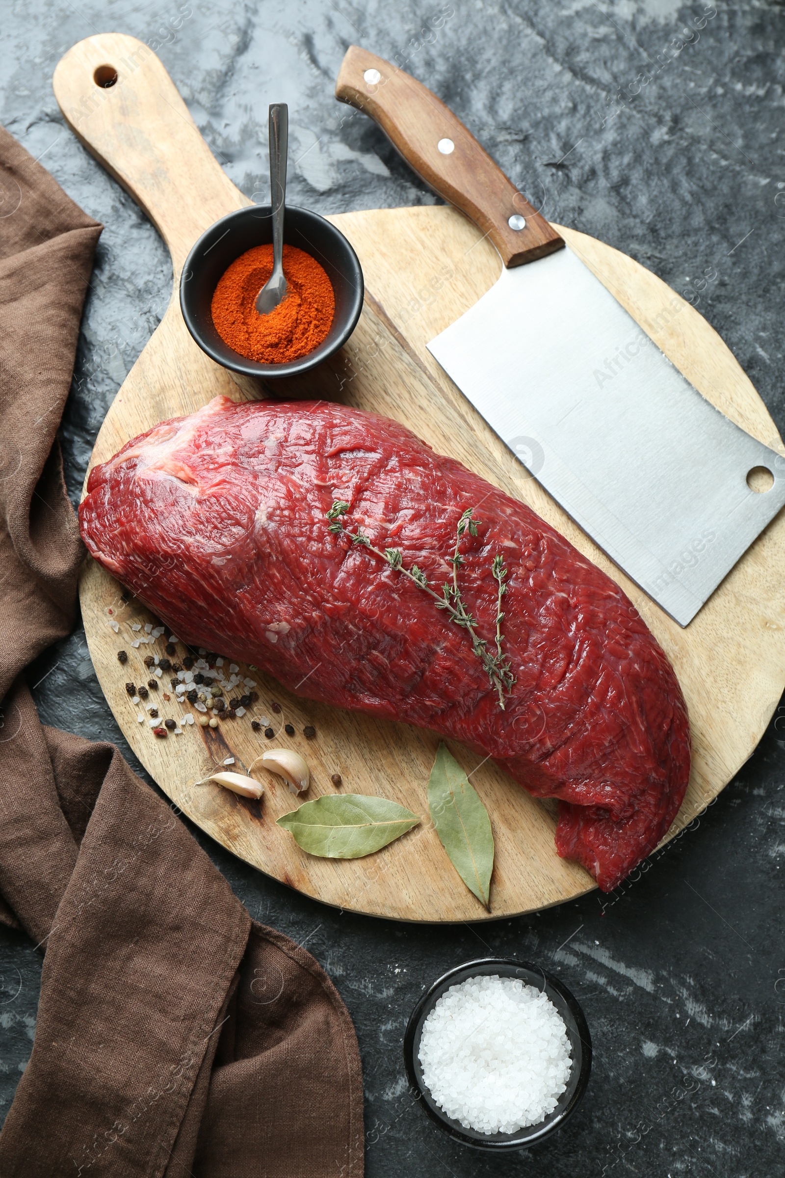 Photo of Piece of raw beef meat, knife and spices on black textured table, flat lay