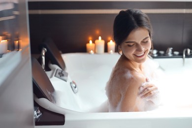 Photo of Happy beautiful woman taking bubble bath. Romantic atmosphere