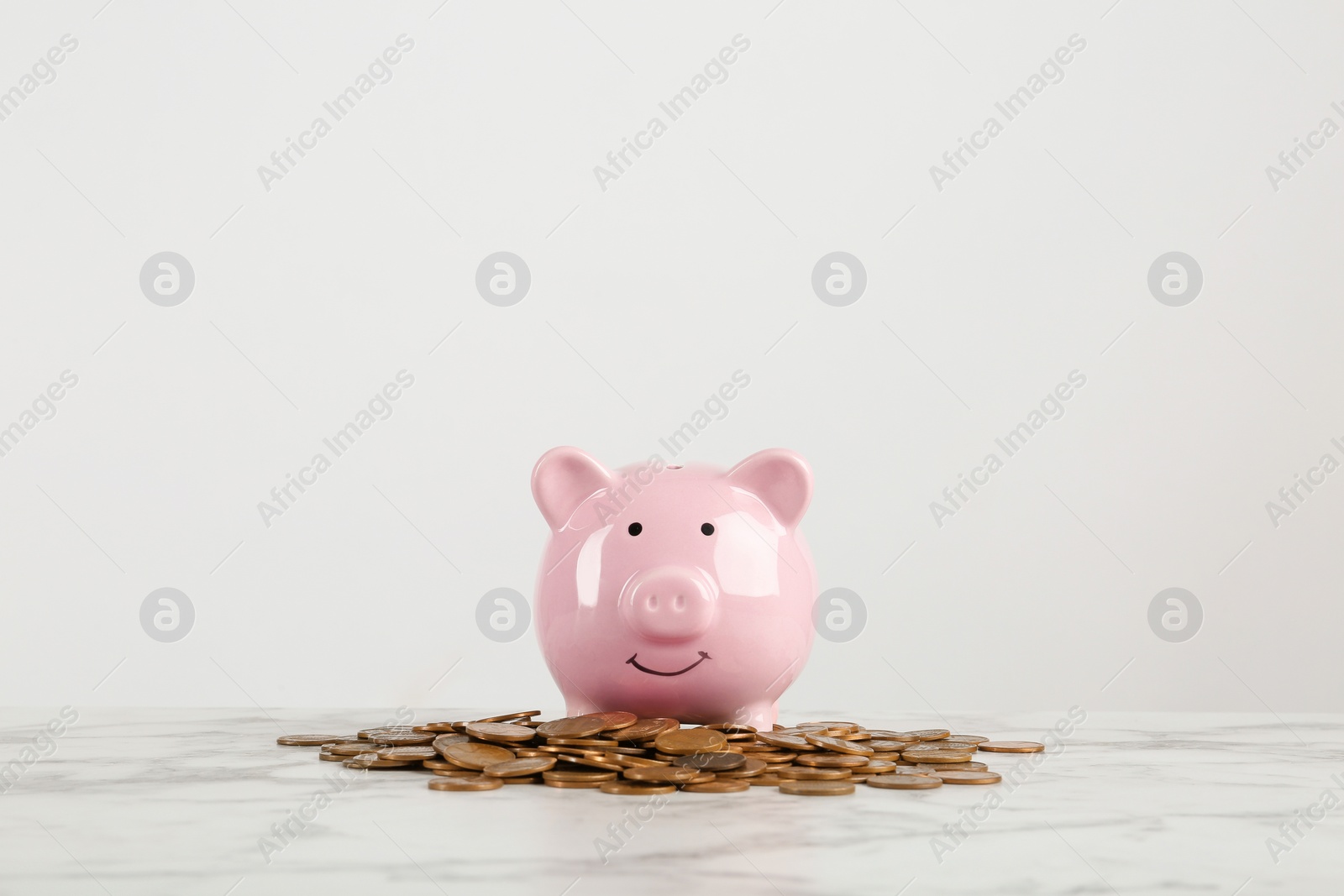 Photo of Piggy bank and coins on table against white background. Space for text