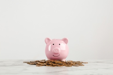 Piggy bank and coins on table against white background. Space for text