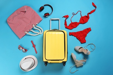 Photo of Flat lay composition with suitcase and accessories on color background. Summer vacation