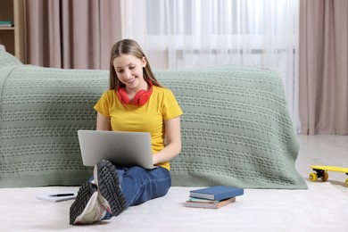 Photo of Online learning. Teenage girl with laptop near bed at home