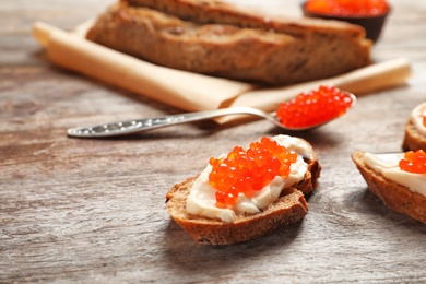 Sandwich with red caviar on wooden table