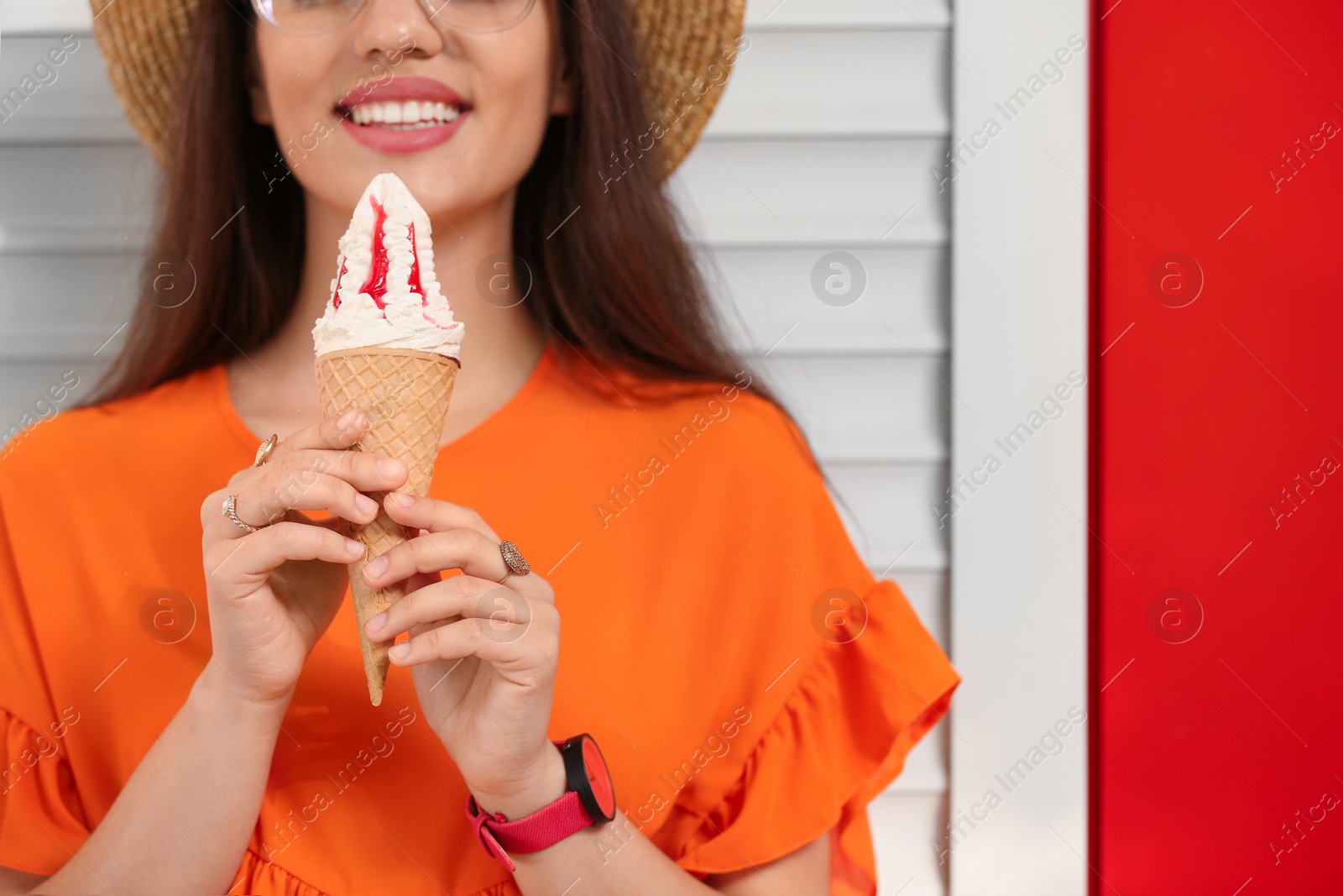 Photo of Happy young woman with delicious ice cream in waffle cone near color wall, closeup. Space for text