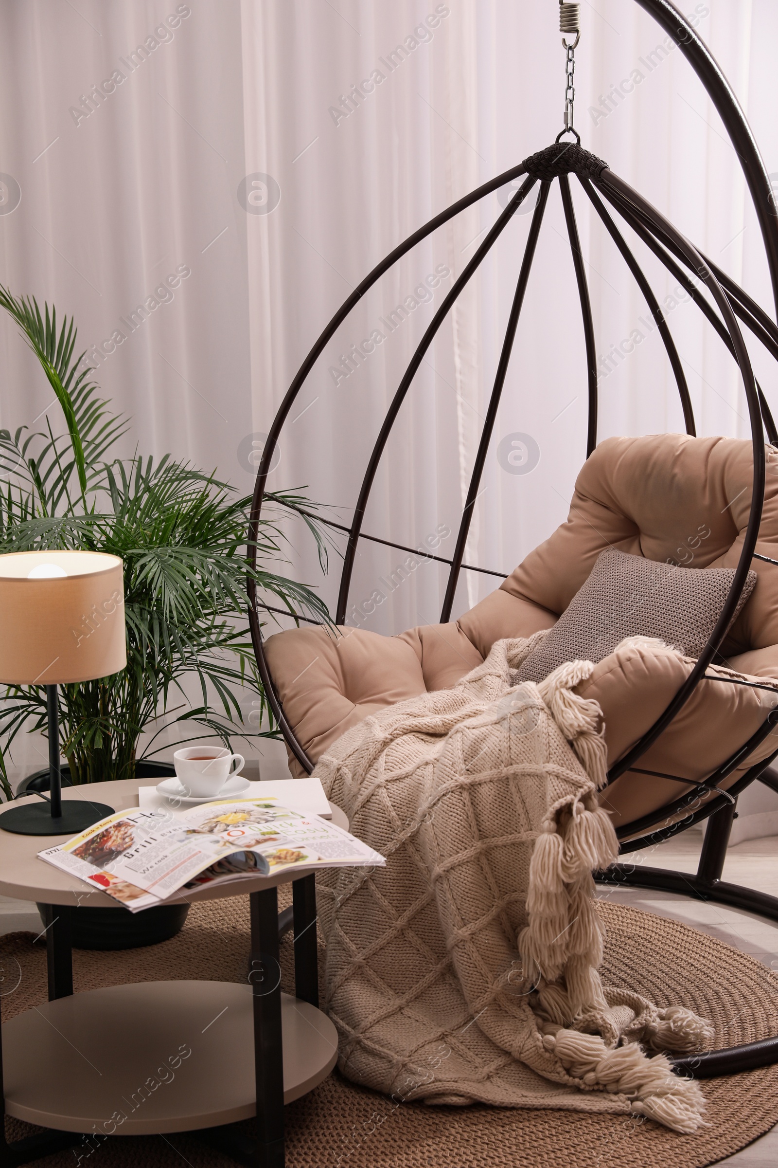 Photo of Comfortable place for rest with hanging chair near window in room