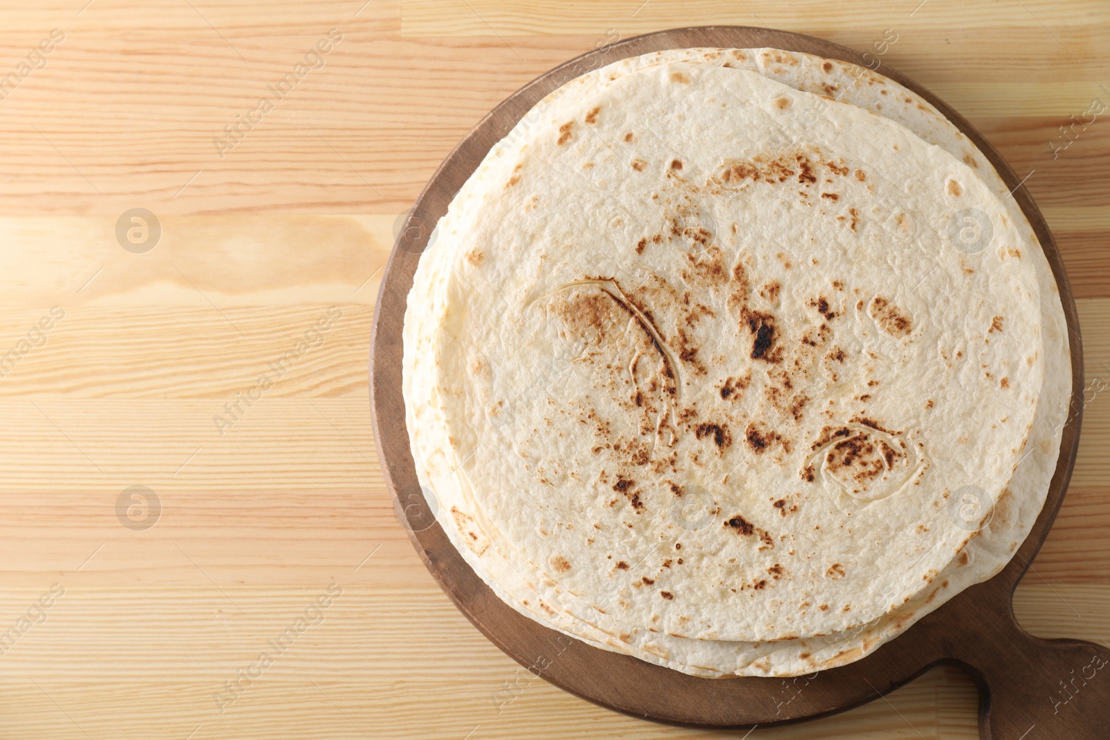 Photo of Many tasty homemade tortillas on wooden table, top view. Space for text