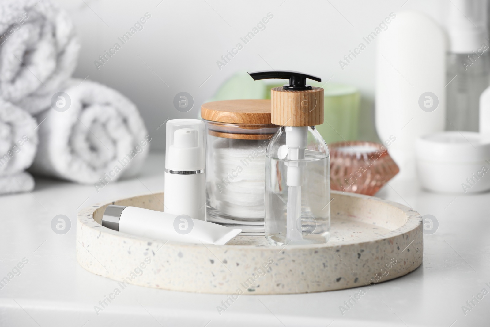 Photo of Tray with dispenser bottle and cosmetic products on white table in bathroom