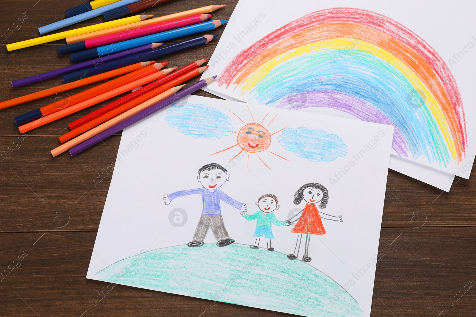 Photo of Cute child`s drawings and colorful pencils on wooden table, flat lay