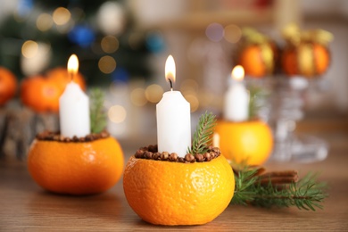 Photo of Burning candle in tangerine peel as holder on wooden table