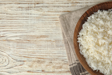 Bowl with tasty cooked rice on white wooden table, flat lay. Space for text