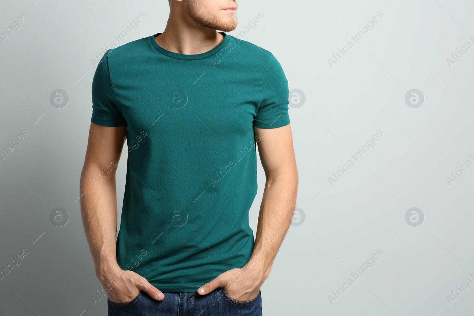 Photo of Young man wearing blank t-shirt on light background, closeup. Mockup for design
