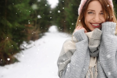 Photo of Young woman in snowy conifer forest, space for text. Winter vacation