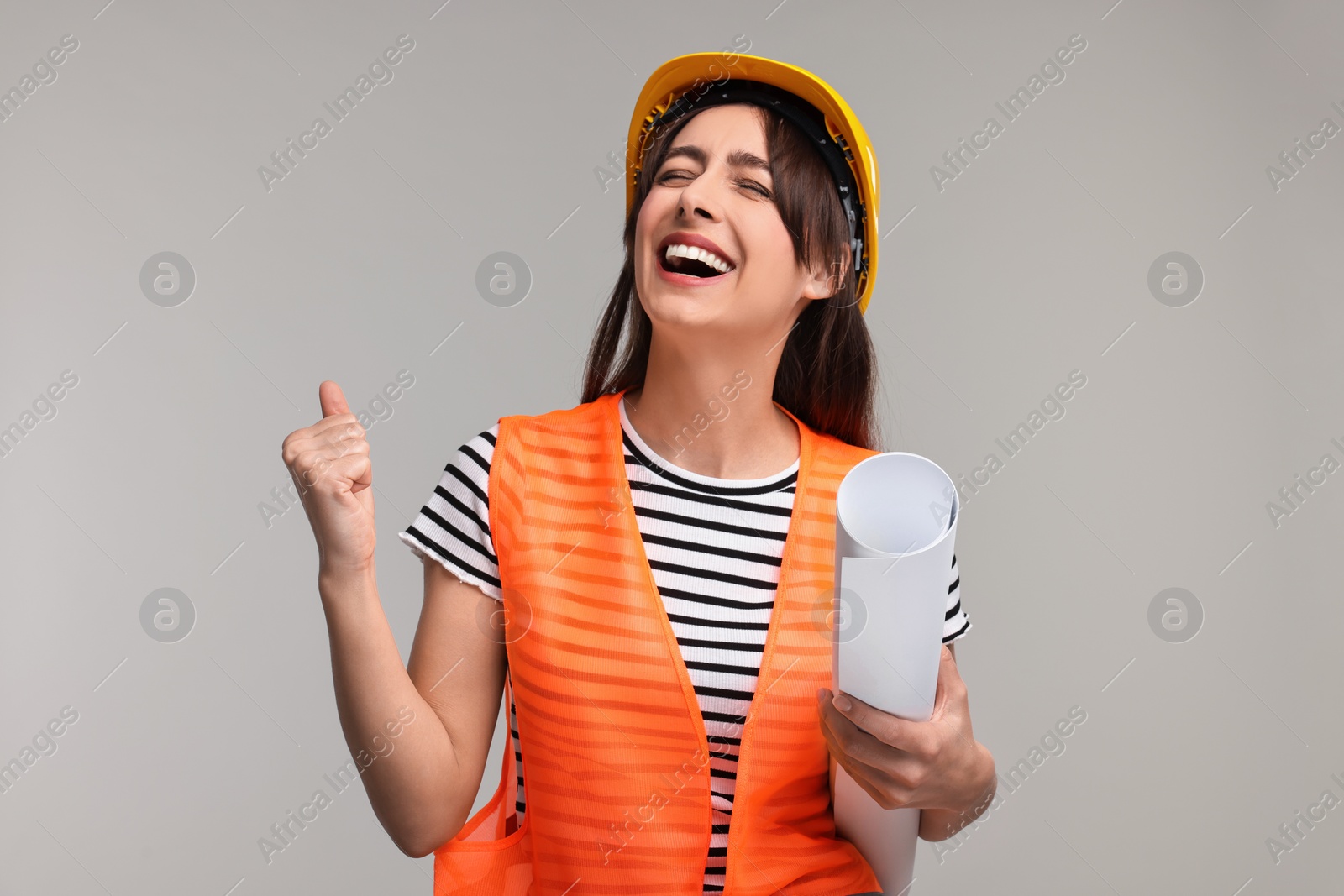 Photo of Architect in hard hat with draft on light grey background