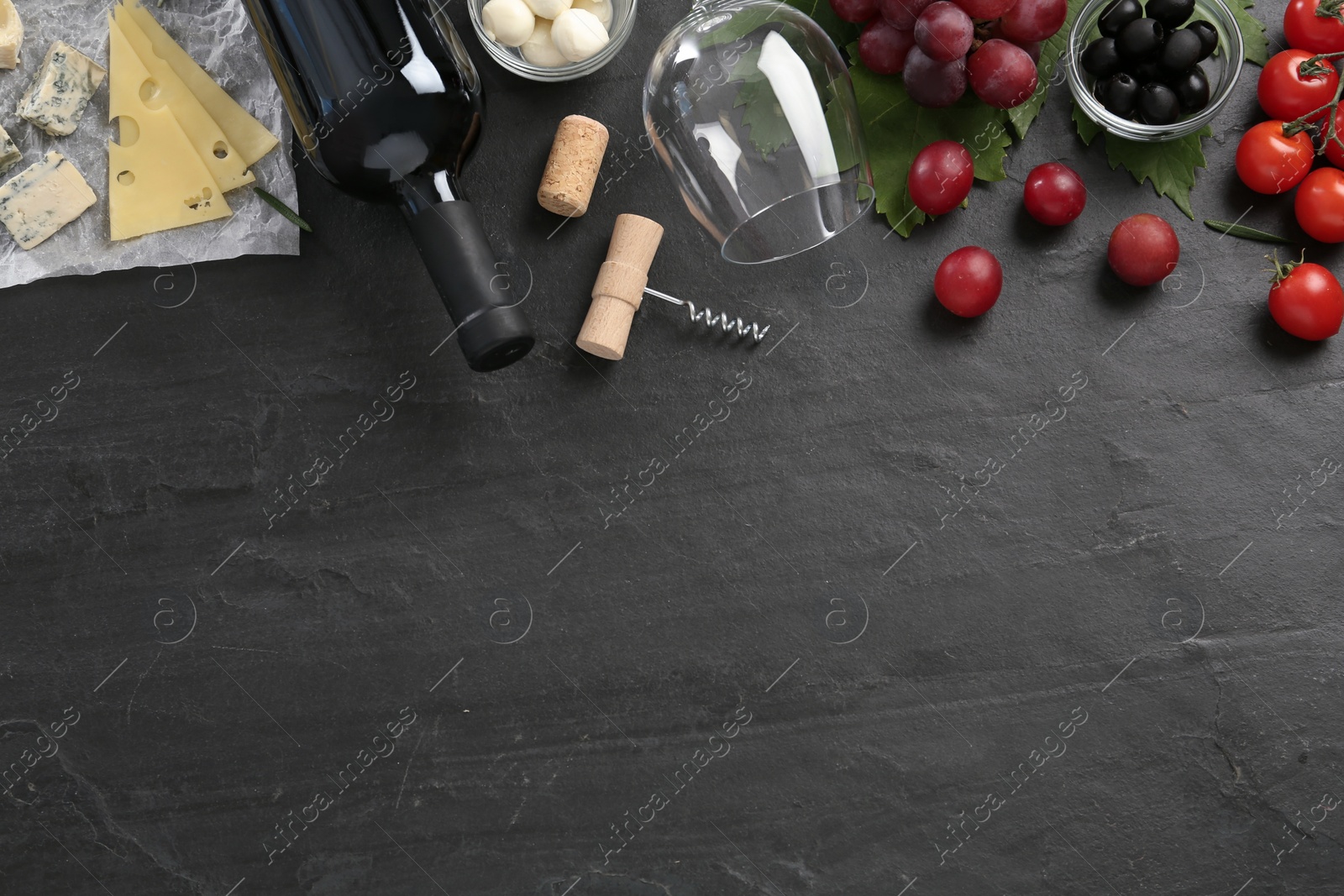 Photo of Tasty red wine and snacks on black table, flat lay. Space for text