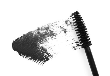 Applicator and black mascara smear on white background, top view