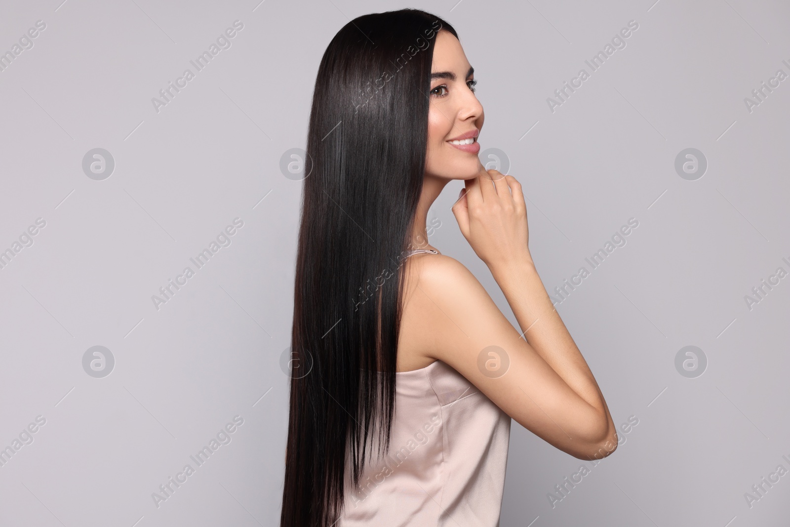 Photo of Portrait of beautiful young woman with healthy strong hair on light grey background