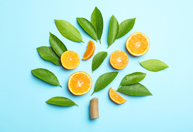 Flat lay composition with fresh green citrus leaves and tangerine slices on light blue background