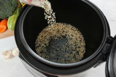 Photo of Pouring rice into modern multi cooker, closeup